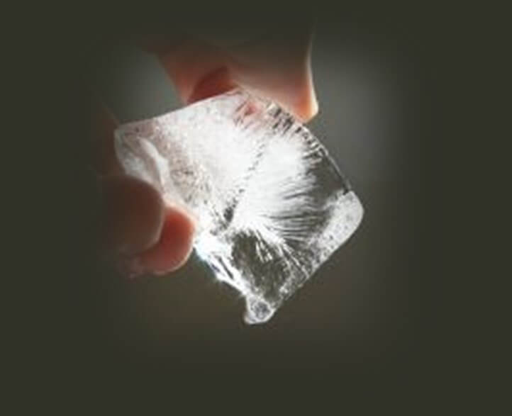 נפיחות בעיניים / שקיות מתחת לעיניים - טיפ קומפרס עם קוביית קרח להורדת נפיחות בעיניים. תמונה של קוביית קרח ביד.